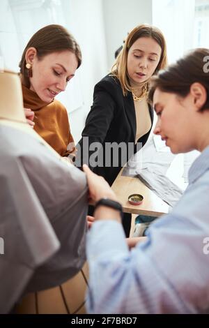 Instructeur de couture ajustant un bout de tissu sur le mannequin Banque D'Images