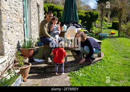 Parents mère père famille assis avec des enfants à l'extérieur de la maison Week-end de Pâques ensoleillé dans un jardin dans l'ouest du pays de Galles au Royaume-Uni KATHY DEWITT Banque D'Images