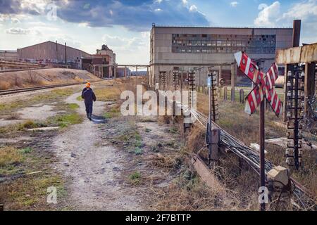 Usine d'extraction et de traitement soviétique dépassée. Panneau de chemin de fer rouge et travailleurs Banque D'Images