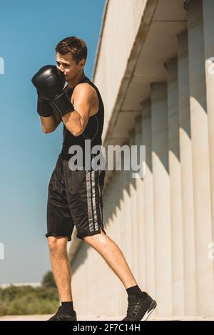 Homme s'exerçant et se battant à l'extérieur, boxeur en gants. Portrait de boxeur masculin Banque D'Images