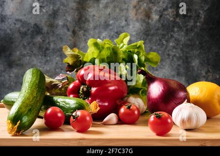 Concombre, tomates, poivrons, ail et laitue sur fond sombre Banque D'Images