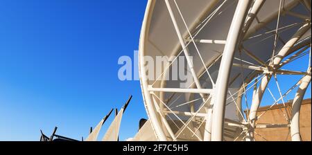 Gros plan d'une structure de traction moderne sur un ciel bleu clair, toit en toile à membrane avec poteaux en acier blanc. Photographie, plein format. Banque D'Images