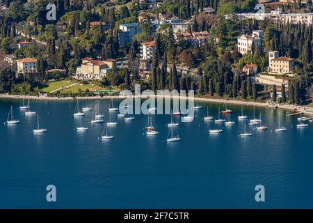 Vue aérienne du port avec des bateaux à voile en face de la ville de Garda, station touristique sur la côte du lac de Garde, Vérone, Vénétie, Italie, Europe. Banque D'Images