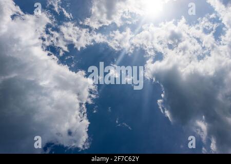 Beau ciel bleu avec des nuages de cumulus blancs et des rayons de soleil. Photographie en contre-jour. Banque D'Images