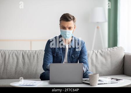 Homme d'affaires dans un masque de protection utilisant un ordinateur portable à la maison Banque D'Images