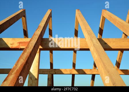 Le cadre de toit en bois se déporte contre un ciel bleu. Banque D'Images