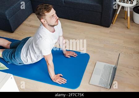 Jeune homme faisant du yoga dans son salon Banque D'Images