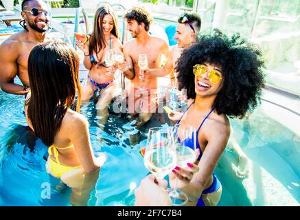 Joyeux groupe d'amis qui s'amusent à la fête au bord de la piscine - Concept d'amitié avec les jeunes riant ensemble en vacances - Focus sur la femme noire Banque D'Images