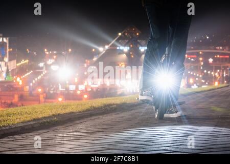 Un homme sur une monoroue électrique s'est arrêté en conduisant dans la ville. Conduite de nuit sur un monocycle électrique (EUC) avec un phare lumineux. Banque D'Images