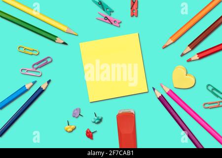 Fournitures de retour à l'école lumineuses avec note adhésive jaune sur fond turquoise. Pose à plat. Banque D'Images