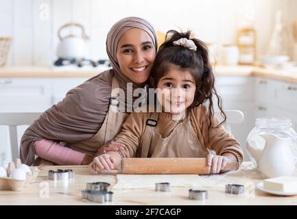 Petite fille drôle et sa belle maman musulmane cuisant ensemble Dans la cuisine Banque D'Images