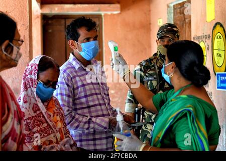 Un professionnel de la santé vérifie la température corporelle d'un électeur lors de l'élection de l'Assemblée législative du Bengale occidental de 2021 à Baruipur. (Photo par Avishek Das / SOPA Images / Sipa USA) Banque D'Images