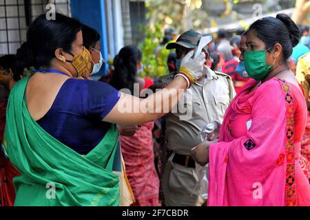 Un professionnel de la santé vérifie la température corporelle d'un électeur lors de l'élection de l'Assemblée législative du Bengale occidental de 2021 à Baruipur. (Photo par Avishek Das / SOPA Images / Sipa USA) Banque D'Images