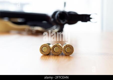Trois balles en bas sur fond flou de carabine d'assaut Kalashnikov. Cartouches calibre 7.62 pour ak 47 gros plan. Banque D'Images