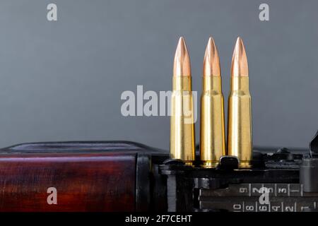Trois balles sur le fusil d'assaut Kalashnikov sur fond gris flou. Cartouches calibre 7.62 pour ak 47, gros plan, mise au point sélective avec fonction de copie Banque D'Images