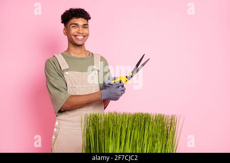 Photo portrait de jardinier en courbure en gardant les ciseaux coupants vert combinaison de port d'herbe isolée sur fond rose pastel Banque D'Images