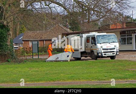 Un matelas à bout de mouche est collecté par les employés de l'entretien des autoroutes d'un petit vert dans le Borough de Hellesdon, Norfolk, Angleterre, Royaume-Uni. Banque D'Images