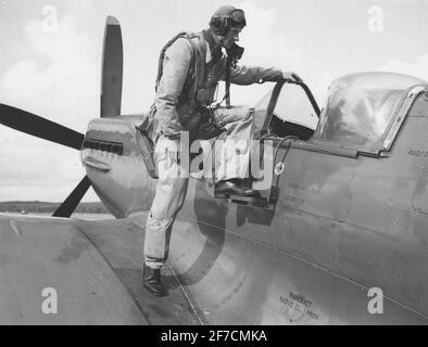 Un homme vêtu de la combinaison de l'avion qui entre dans le Spitfire 31 de l'avion. Un homme vêtu de la combinaison de l'avion qui entre dans le Spitfire 31 de l'avion. Banque D'Images