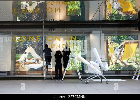 Londres, Royaume-Uni - 6 avril 2021 : les employés du magasin John Lewis d'Oxford Street apposent des panneaux pour accueillir les clients avant que les règles de la feuille de route de confinement en Angleterre permettent aux magasins de rouvrir le 12 avril. Banque D'Images