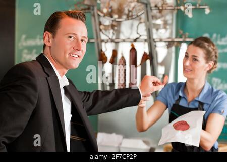 Portrait of handsome businessman smiling avec butcher en arrière-plan la viande holding Banque D'Images