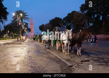 Buggies à cheval et mosquée de Koutoubia en arrière-plan tôt le matin à Marrakech, au Maroc Banque D'Images