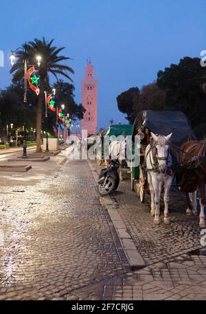 Buggies à cheval et mosquée de Koutoubia en arrière-plan tôt le matin à Marrakech, au Maroc Banque D'Images