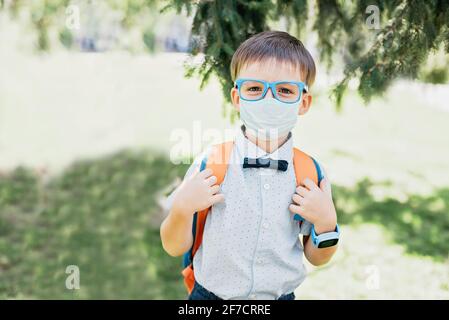 Portrait d'un élève en lunettes et papillon portant un masque médical. Retour à l'école. Enfant intelligent. Concept d'apprentissage, d'esprit et de réussite en quarantaine Banque D'Images