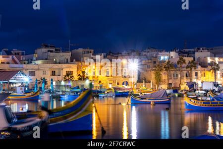 Marsaxlokk, Malte, 28 févr. 2020. Port de Marsaxlokk avec bateaux de pêche colorés et lumières de la rue dans la nuit. Banque D'Images