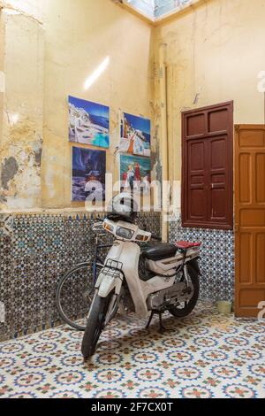 Scooter automobile typique dans une cour magnifiquement carrelée à Marrakech, Maroc Banque D'Images