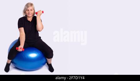 Bannière, format long, fond gris avec espace pour les publicités. Blonde gai forte sportive fitness femme senior portant un survêtement faire des exercices avec Banque D'Images