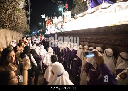 Les Cucuruchos en robes violettes se déroulent solennellement dans les rues d'Antigua, au Guatemala, pendant les célébrations traditionnelles de la semaine Sainte de Semana Santa. Banque D'Images