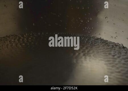 Bol de chant tibétain plein d'eau gros plan sur les gouttes d'eau, instrument de guérison sonore Banque D'Images