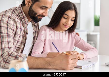 Joyeux père indien aidant enfant école adolescent fille apprenant à la maison. Banque D'Images