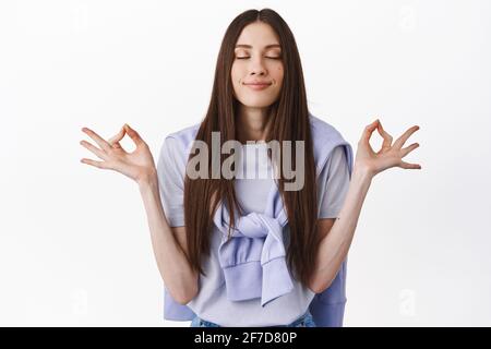 Pensées positives seulement. Jeune femme souriante méditant, pratiquer le yoga avec les yeux fermés, respirer calme et détendu, se reposer, avoir la paix à l'esprit Banque D'Images