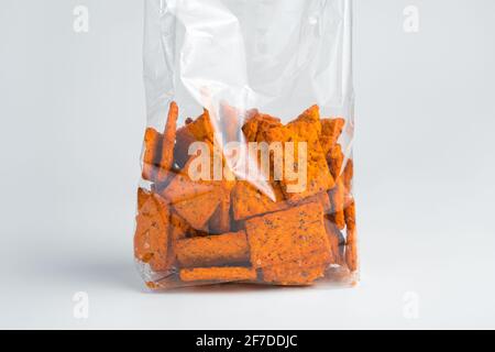 Craquelins à la tomate au sel de mer et basilic avec un sac d'emballage. Vue latérale, gros plan. Banque D'Images