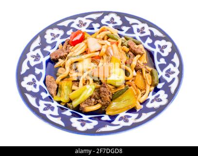 Agneau cuit avec des nouilles de blé et des légumes cuits sur une authentique assiette orientale. Isolé sur un fond blanc. Banque D'Images