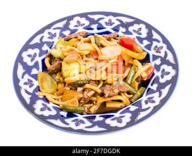 Agneau cuit avec des nouilles de blé et des légumes cuits sur une authentique assiette orientale. Isolé sur un fond blanc. Banque D'Images