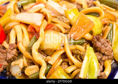 Agneau cuit avec des nouilles de blé et des légumes cuits sur une authentique assiette orientale. Macro. La photo peut être utilisée comme arrière-plan entier. Banque D'Images