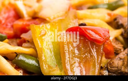 Agneau cuit avec des nouilles de blé et des légumes cuits sur une authentique assiette orientale. Macro. La photo peut être utilisée comme arrière-plan entier. Banque D'Images