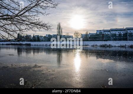 soleil se reflétant à la belle rivière gelée appelé werdersee au soleil journée d'hiver chaude et blanche avec digue enneigée à brême le soir Banque D'Images