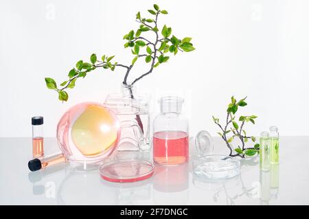 Laboratoire vert naturel. Motif fleuri abstrait. Produit liquide orange dans un récipient pour produits chimiques. Réflexions de brindilles déformées dans l'eau. Vert printemps Banque D'Images