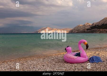 Vue sur un anneau gonflable de natation avec flamants roses sur la plage de Baska, Croatie Banque D'Images