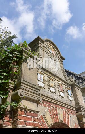 La porte Westerhuis Vrouwengasthuis du XVIIe siècle est ornée de armoiries colorées en Franeker. Derrière elle, trois blocs de maisons autour d'une cour. Banque D'Images