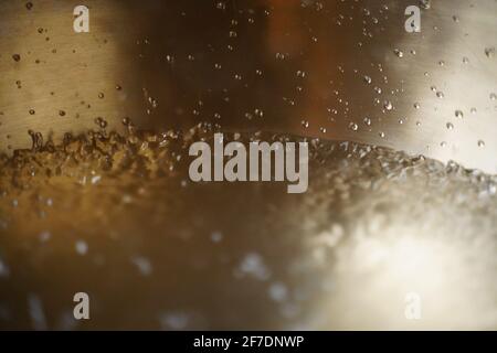Bol de chant tibétain plein d'eau gros plan sur les gouttes d'eau, instrument de guérison sonore Banque D'Images