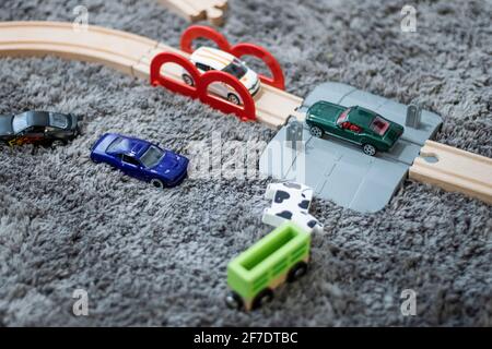 Petites voitures jouets en métal sur un sol gris avec moquette aire de jeux en bois Banque D'Images