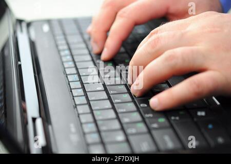 Les mains des hommes de la saisie sur un clavier d'ordinateur portable Banque D'Images