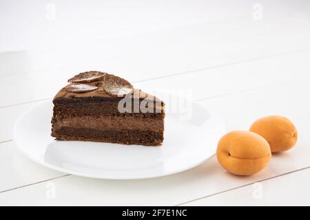 Morceau de gâteau fait maison au chocolat avec des noix et de la gelée d'abricot dans une assiette Banque D'Images