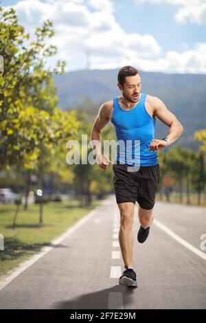 Portrait sur toute la longueur d'un coureur mâle vérifiant le temps un chemin d'exécution Banque D'Images