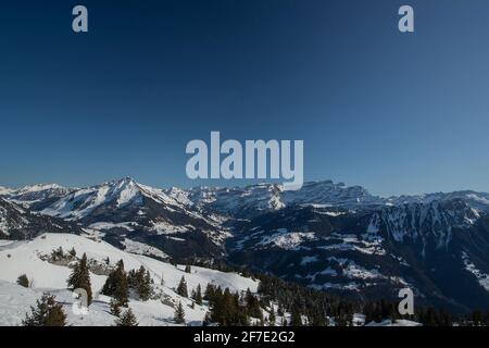 Magnifique panorama de montagne depuis le massif de Leysin par une journée d'hiver nuageux. Vue sur le centre de ski et la vallée des Diablerets. Banque D'Images