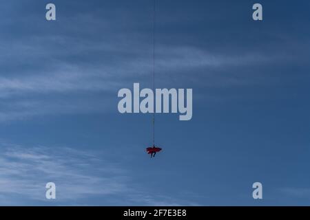 Paramédic est accroché sur une ligne à côté d'une personne blessée dans un brancard après avoir été blessé dans les montagnes. Sauvetage en montagne avec un hélicoptère Banque D'Images